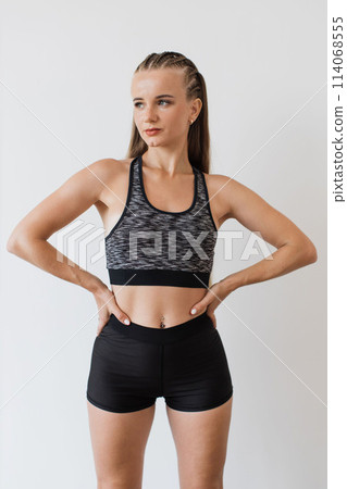 Confident young woman poses in fitness attire indoors 114068555