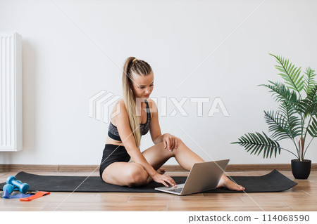 Young woman planning her workout routine on a laptop 114068590