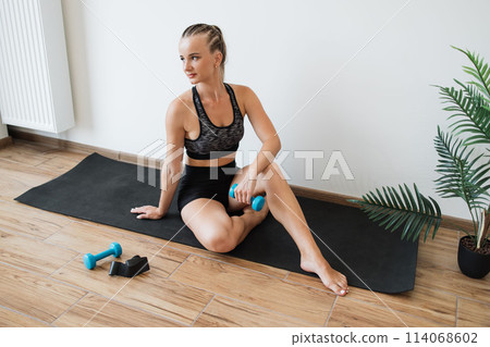 Young woman exercising with dumbbells in a bright room Young woman exercising with dumbbells in a bright room 114068602