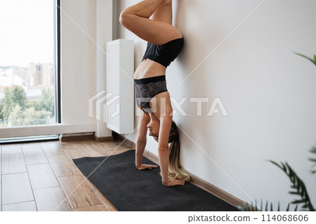 Athletic Woman Performing a Handstand in Modern Home Gym Athletic Woman Performing a Handstand in Modern Home Gym 114068606