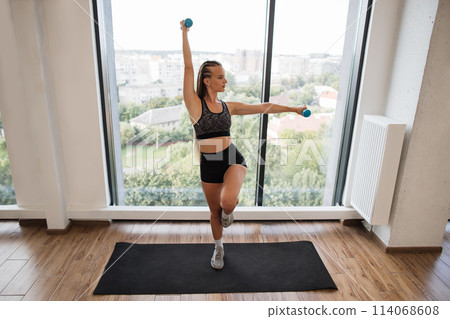 Fitness Enthusiast Exercising Balance and Strength in a Bright Studio 114068608