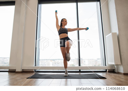 Fitness Enthusiast Exercising Balance and Strength in a Bright Studio 114068610