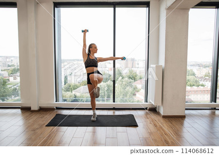 Fitness Enthusiast Exercising Balance and Strength in a Bright Studio Fitness Enthusiast Exercising Balance and Strength in a Bright Studio 114068612
