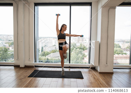 Fitness Enthusiast Exercising Balance and Strength in a Bright Studio Fitness Enthusiast Exercising Balance and Strength in a Bright Studio 114068613