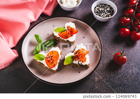 Heart sandwiches with ricotta and tomatoes on rye bread on a plate 114069743