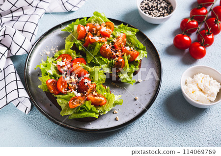 Sandwich with tomatoes and lettuce on rye bread on a plate on the table 114069769