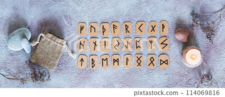 Scandinavian runes for fortune telling, pouch and candle on the table top view web banner Scandinavian runes for fortune telling, pouch and candle on the table top view web banner 114069816