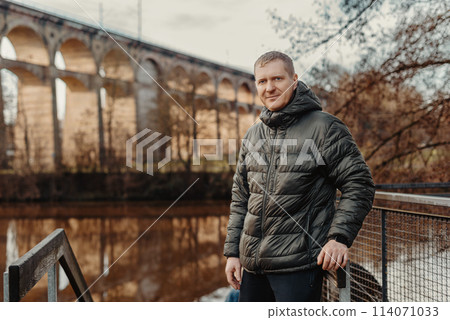 Timeless Elegance: 40-Year-Old Man in Stylish Jacket by Neckar River and Historic Bridge in Bietigheim-Bissingen, Germany Timeless Elegance: 40-Year-Old Man in Stylish Jacket by Neckar River and Historic Bridge in Bietigheim-Bissingen, Germany 114071033