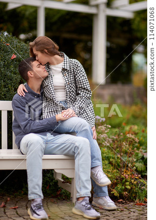 Autumn Romance: Young Couple Embracing and Kissing on Park Bench. Young couple kissing and rejoices at the lake. lovely young couple kissing outdoors in autumn. Embraced in Autumn's Warmth: Couple's Autumn Romance: Young Couple Embracing and Kissing on Park Bench. Young couple kissing and rejoices at the lake. lovely young couple kissing outdoors in autumn. Embraced in Autumn's Warmth: Couple's 114071068