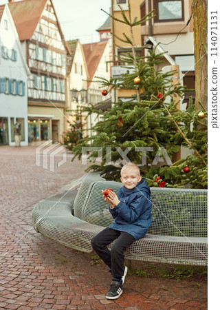 Winter Wonderland Delight: 8-Year-Old Boy with Christmas Decor by Vintage Fountain. Winter Wonderland Delight: 8-Year-Old Boy with Christmas Decor by Vintage Fountain. 114071131
