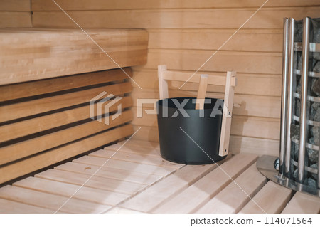 A wooden bench with a black bucket on it. The bucket is filled with water and a wooden stick. A wooden bench with a black bucket on it. The bucket is filled with water and a wooden stick. 114071564