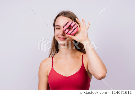 Young cute sport woman eating a donut cake in studio background 114071611