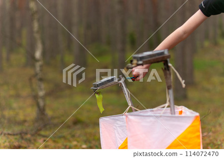 A boy punching at the orienteering control point 114072470