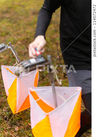 A boy punching at the orienteering control point 114072472