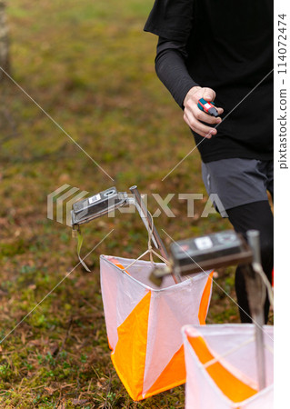 A boy punching at the orienteering control point 114072474