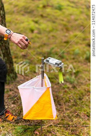 The elderly woman punching at the orienteering control point 114072475