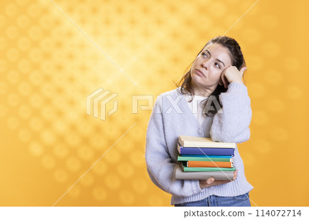 Portrait of relaxed woman daydreaming while holding pile of books, enjoying reading hobby. Person with stack of novels in arms caught in reverie while enjoying leisure time, studio background Portrait of relaxed woman daydreaming while holding pile of books, enjoying reading hobby. Person with stack of novels in arms caught in reverie while enjoying leisure time, studio background 114072714