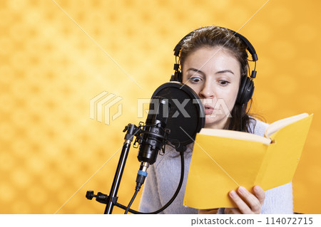 Narrator with shocked look on face reading horror book, recording audiobook using microphone, studio background. Woman with fearful facial expression producing digital recording of novel Narrator with shocked look on face reading horror book, recording audiobook using microphone, studio background. Woman with fearful facial expression producing digital recording of novel 114072715