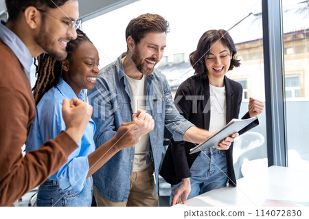 Smiling diverse colleagues celebrating success with clenched fists in coworking environment 114072830