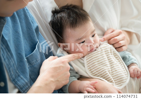 年輕的父母抱著一個臉頰發麻的嬰兒。 年輕的父母抱著一個臉頰發麻的嬰兒。 114074731