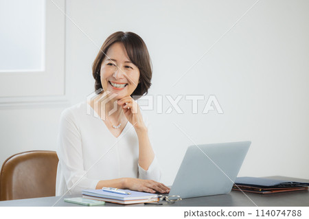 A senior woman operating a computer 114074788