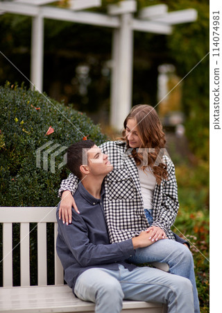 Autumn Romance: Young Couple Embracing and Kissing on Park Bench. Young couple kissing and rejoices at the lake. lovely young couple kissing outdoors in autumn. Embraced in Autumn's Warmth: Couple's Autumn Romance: Young Couple Embracing and Kissing on Park Bench. Young couple kissing and rejoices at the lake. lovely young couple kissing outdoors in autumn. Embraced in Autumn's Warmth: Couple's 114074981