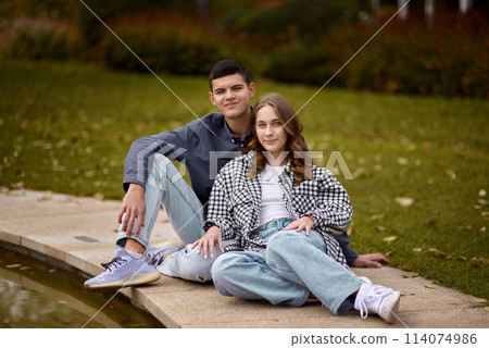 Young couple kissing and rejoices at the lake. lovely young couple kissing outdoors in autumn. Loving couple walking in nature. Autumn mood. Happy man and woman hugging and kissing in autumn. Love 114074986