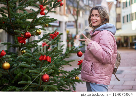 A beautiful girl stands on the street of the old European town of Bietigheim-Bissingen in Germany on Christmas Eve. Festive Flair: Bietigheim-Bissingen's Christmas Tale. City streets are decorated 114075004