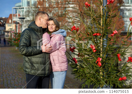 Portrait of young attractive people, lovely couple enjoying cozy atmosphere on fair in Christmas Eve. Spending time together. Concept of national traditions, winter holidays, fashion, festivities Portrait of young attractive people, lovely couple enjoying cozy atmosphere on fair in Christmas Eve. Spending time together. Concept of national traditions, winter holidays, fashion, festivities 114075015