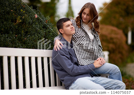 Autumn Romance: Young Couple Embracing and Kissing on Park Bench. Young couple kissing and rejoices at the lake. lovely young couple kissing outdoors in autumn. Embraced in Autumn's Warmth: Couple's Autumn Romance: Young Couple Embracing and Kissing on Park Bench. Young couple kissing and rejoices at the lake. lovely young couple kissing outdoors in autumn. Embraced in Autumn's Warmth: Couple's 114075037
