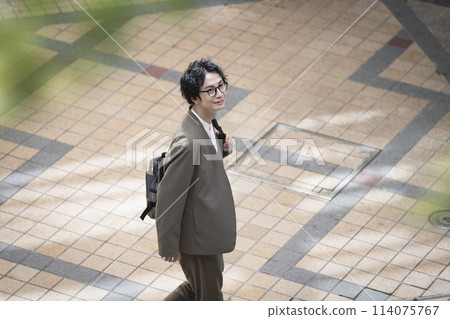 A man in his 30s walking down the street 114075767
