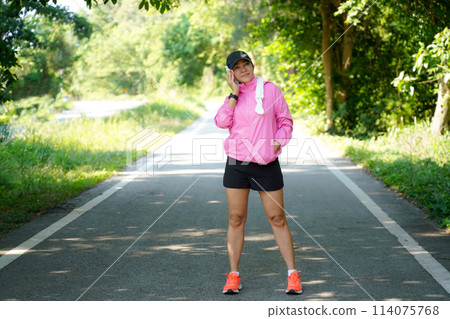 Healthy woman warming up before jogging run and relax stretching her arms and looking away in the road  114075768