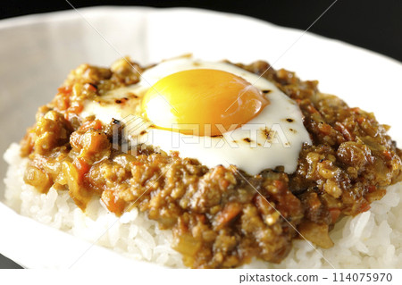 Keema curry with egg yolk and burnt cheese photographed against a black background Keema curry with egg yolk and burnt cheese photographed against a black background 114075970