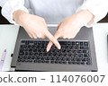 A woman making a cross with her fingers in front of a computer 114076007