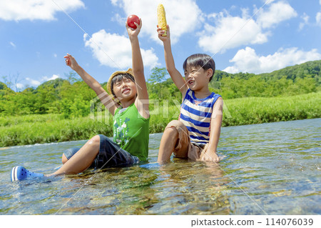 Boys holding summer vegetables on a riverbank in summer Boys holding summer vegetables on a riverbank in summer 114076039