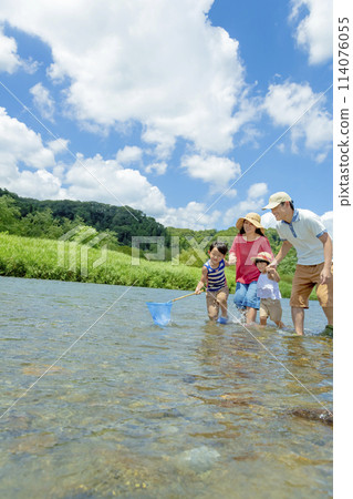 A family of four playing on a river in summer 114076055