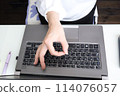 A woman making a circle with her fingers in front of a computer 114076057