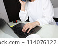 A woman making a phone call in front of a computer 114076122