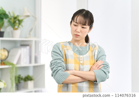 A woman wearing an apron who is worried 114076316