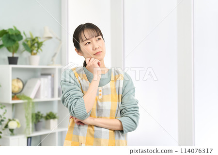 A woman wearing an apron thinking A woman wearing an apron thinking 114076317