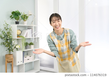 A woman wearing an apron welcoming 114076319