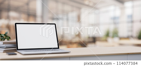 A laptop on a table with a blurred background of a spacious luxurious cafe coffee shop or restaurant 114077384