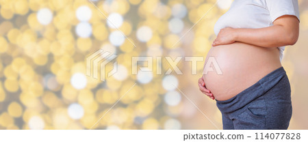 pregnant woman holding her pregnant belly over holiday bokeh lights background 114077828