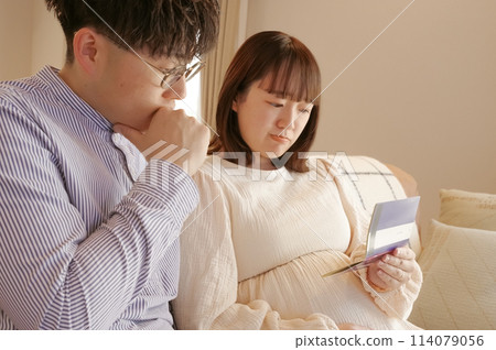 一名孕婦和一名男子一邊看銀行存摺一邊交談 114079056