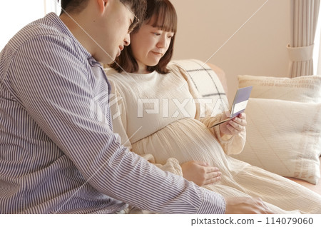 一名孕婦和一名男子一邊看銀行存摺一邊交談 一名孕婦和一名男子一邊看銀行存摺一邊交談 114079060
