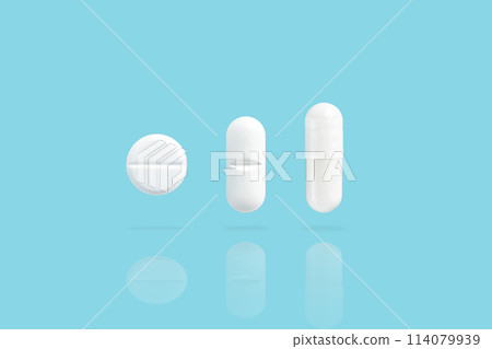 Various white medicine pills levitate over a blue background. Shadow and reflection from drugs 114079939