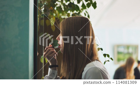 A schoolgirl paints her lips in front of the mirror. A schoolgirl paints her lips in front of the mirror. 114081309