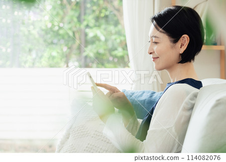 A housewife operating a smartphone in the living room A housewife operating a smartphone in the living room 114082076