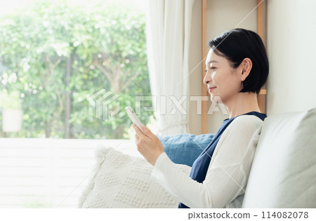A housewife operating a smartphone in the living room 114082078