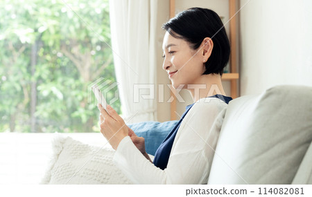 A housewife operating a smartphone in the living room 114082081